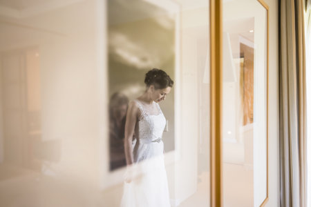 Reflection Of Female Friend Zipping Up Brides Wedding Dress In Hotelの写真素材