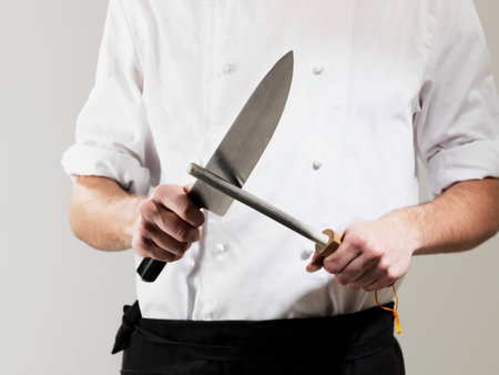 Chef Sharpening Knife Against White Backgroundの写真素材