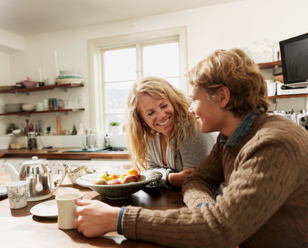 Mother And Teenage Son Sitting At Kitchen Tableの写真素材