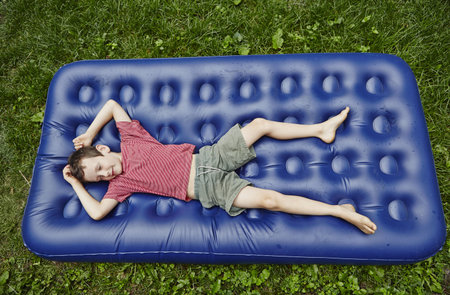 Overhead View Of Boy Lying On Inflatable Mattressの写真素材