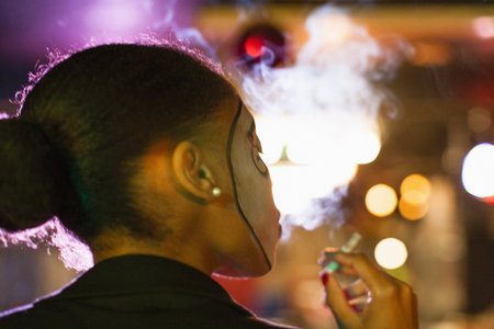 Rear View Of Young Woman In Nightclub Smoking Cigarette