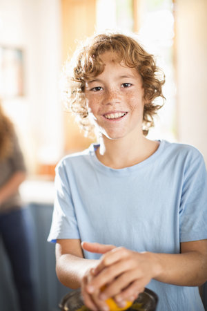 Teenage Boy Juicing Orange In Kitchenの写真素材