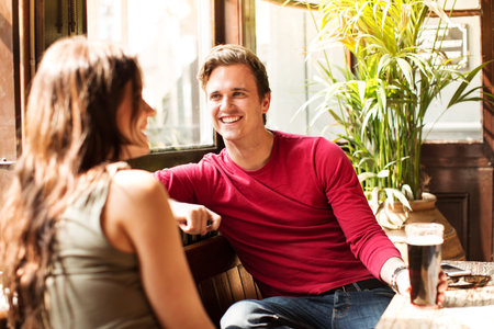 Couple Sitting Together Smiling Enjoying A Drinkの写真素材
