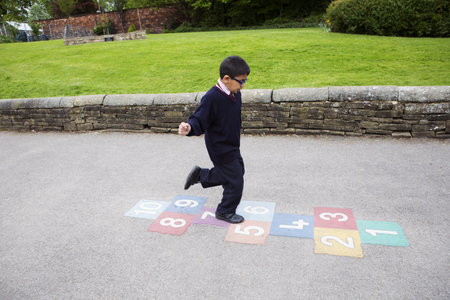 Boy Playing Hopscotch In Playgroundの写真素材