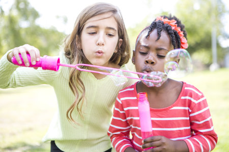 Girls Blowing Bubbles In Parkの写真素材