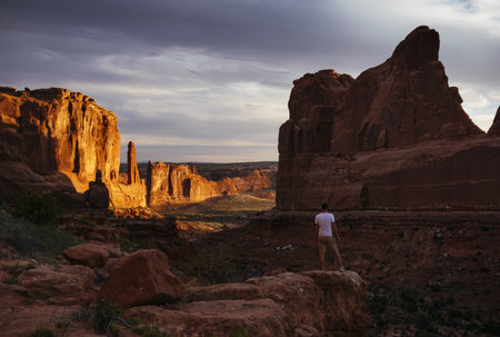 Man Standing In Park Avenue At Dawn, Arches National Park, Utah, Usaの写真素材
