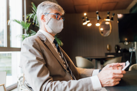 Italy, Businessman in face mask using tablet in creative studioの写真素材