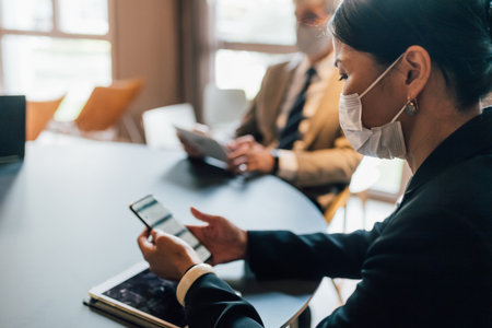Italy, Business people in face masks working at table in officeの写真素材