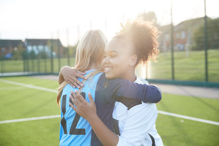 UK, Smiling female soccer team members (12-13) embracing in fieldの写真素材