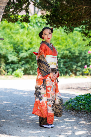 Portrait of woman wearing kimono standing in parkの写真素材