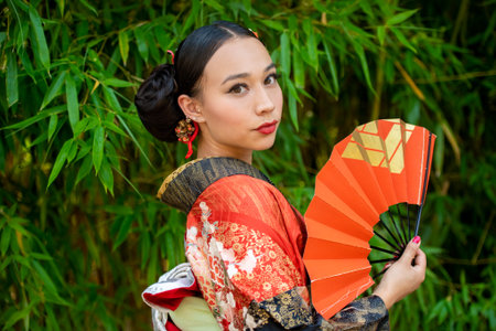 Portrait of woman wearing kimono and holding fanの写真素材