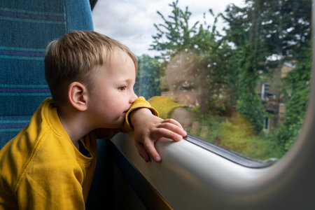 Boy (18-23 months) looking through window in train
