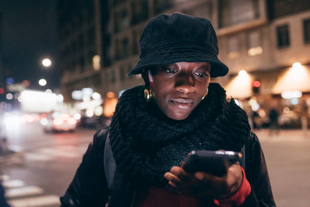 Italy, Woman looking at smart phone in city at nightの写真素材