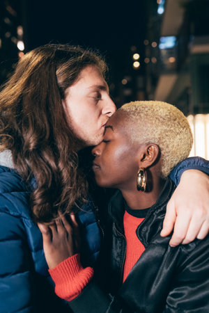 Italy, Man kissing woman's foreheadÃin city at nightの写真素材