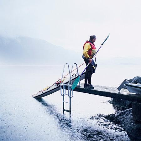 Man pulling kayak onto dockの写真素材