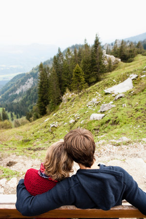 Couple sitting on bench huggingの写真素材