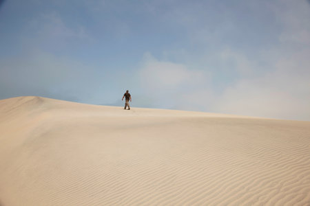 Man walking on sand dunesの写真素材