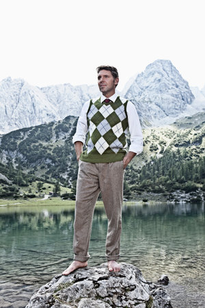 Man in bare feet standing by lakeの写真素材