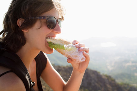 Woman eating sandwich outdoorsの写真素材
