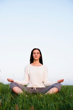 Smiling woman meditating in parkの写真素材