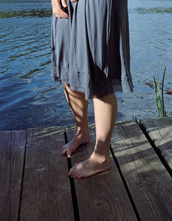 Woman in bare feet standing on dockの写真素材