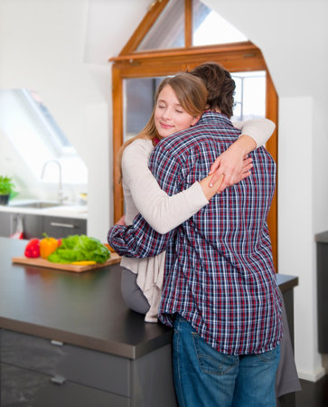 Couple hugging in kitchenの写真素材