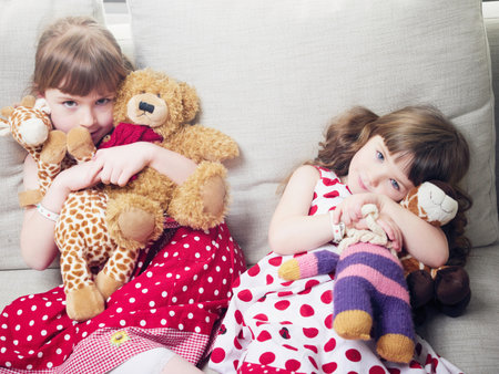 Girls holding stuffed animals on sofaの写真素材