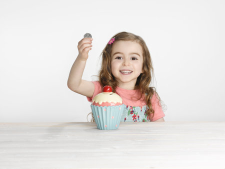 Girl putting coins in cupcake jarの写真素材