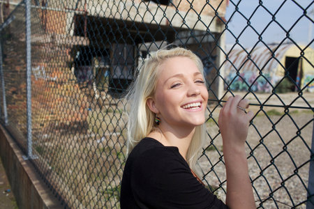 Smiling girl leaning against fenceの写真素材
