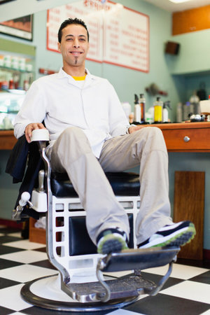Barber sitting in chair in shopの写真素材