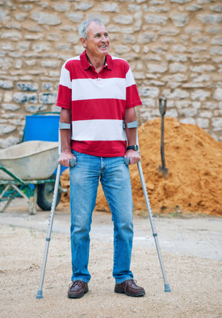 Older man standing with crutchesの写真素材