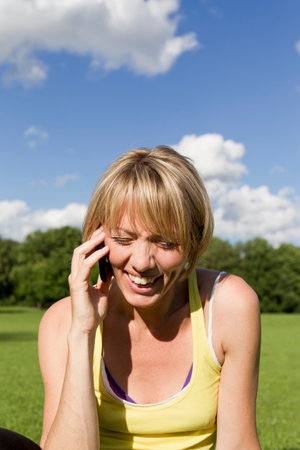 Woman laughing on cell phone outdoorsの写真素材