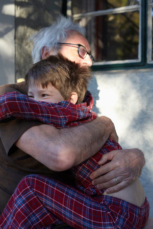 Older man hugging grandson outdoors