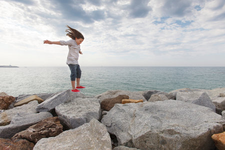 Girl playing on rocks at beachの写真素材