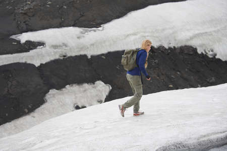 Hiker walking on snowy hillsideの写真素材