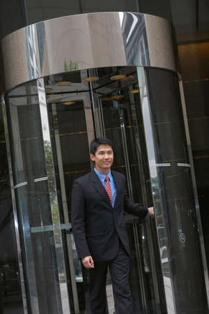 Businessman exiting revolving doorの写真素材