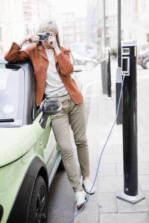 Woman taking picture on city streetの写真素材