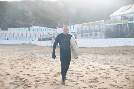 Surfer carrying board on beachの写真素材