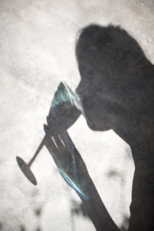 Shadow of woman drinking wine