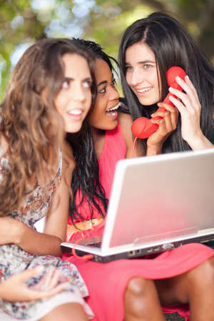 Women using laptop and phone whilst sitting on a tree branchの写真素材