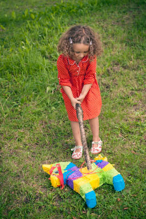 Girl opening pinata on ground at partyの写真素材
