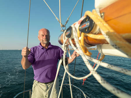 Man adjusting rigging on sailboat