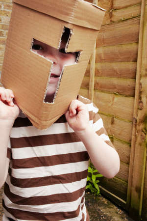Boy wearing cardboard helmet outdoorsの写真素材