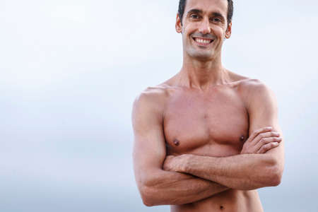 topless man smiling outdoors