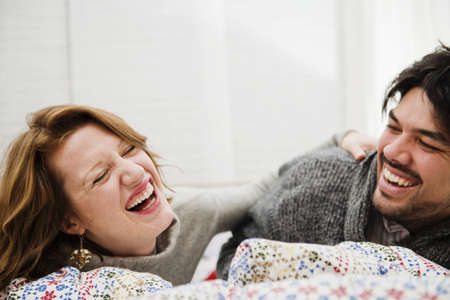 Couple laughing together on bedの写真素材