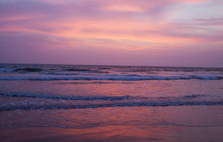 Sunset over waves on beachの写真素材