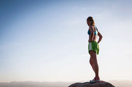 Woman on boulder overlooking landscapeの写真素材