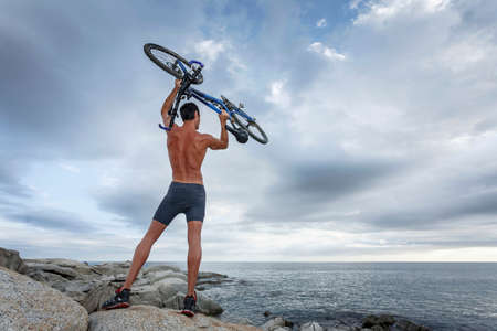 Man holding bicycle on boulderの写真素材
