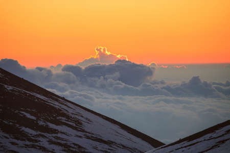 Sun rising over clouds