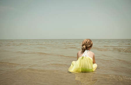 Girl playing in waves on beachの写真素材